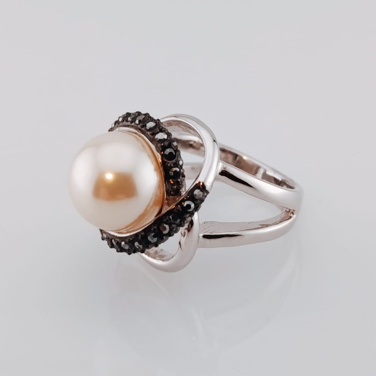 A ring with a central pearl surrounded by black crystal accents, with a gold-colored band.