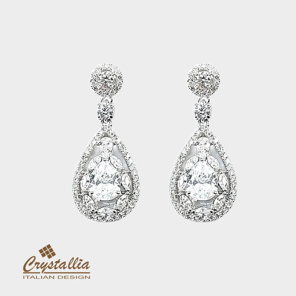 Teardrop-shaped crystal earrings on a light gray background with Crystallia logo.