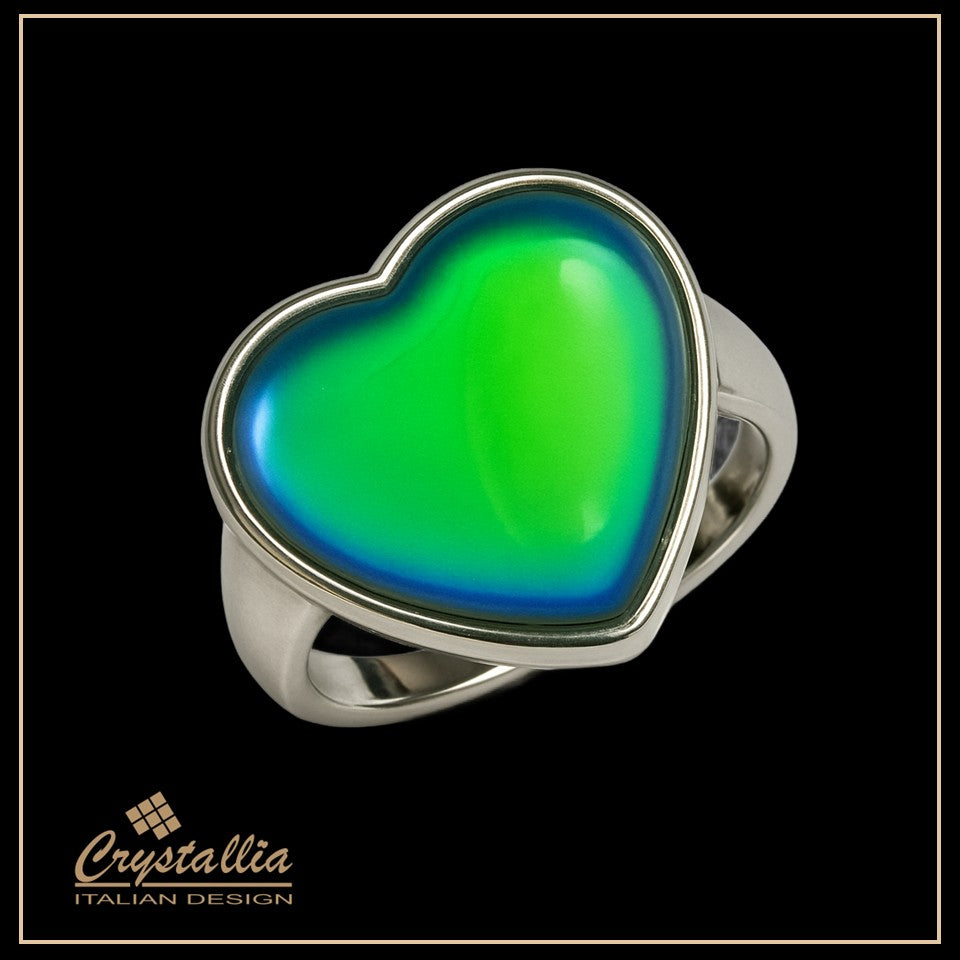 Heart-shaped ring with green and blue colors on a black background, featuring the brand 'Crystallia'.