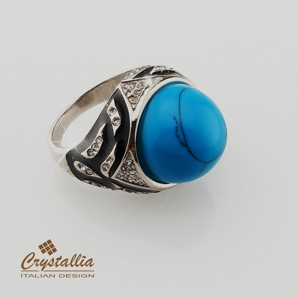 Silver ring with a blue stone on a light gray background, featuring the Crystallia brand.