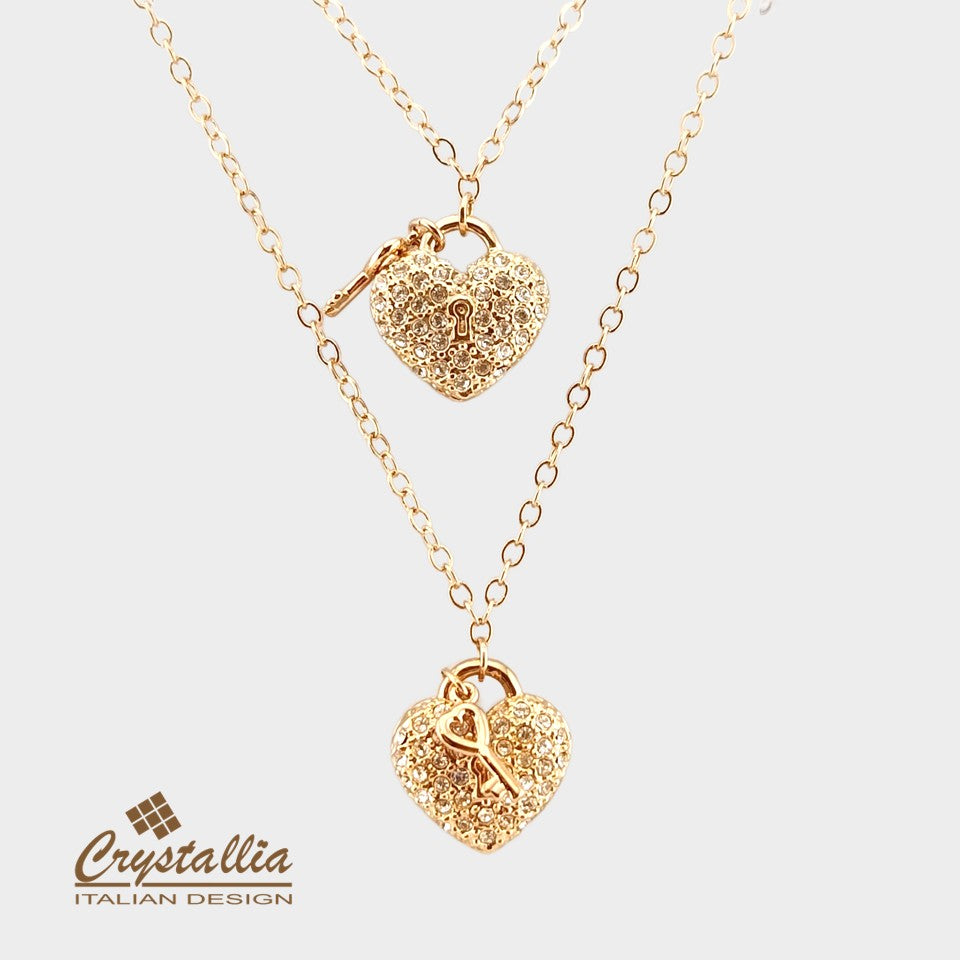 Gold heart-shaped necklace with lock clasp on a light gray background, featuring the Crystallia brand.