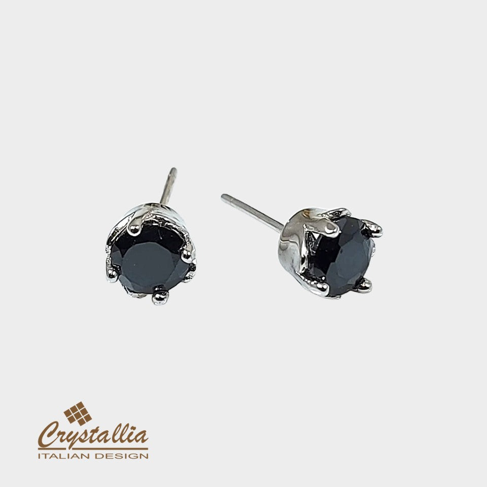 Pair of black gemstone stud earrings with silver settings on a white background, featuring the Crystallia brand.