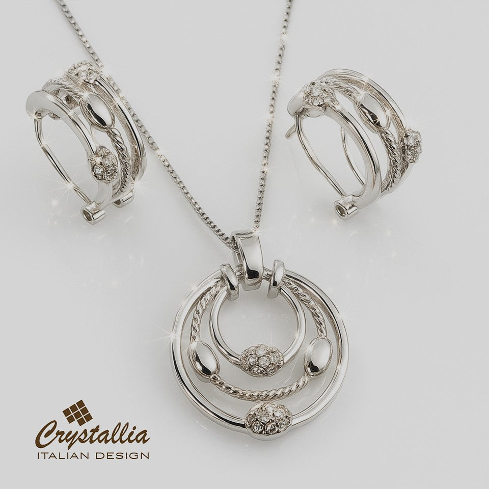 Silver jewelry set with pendant, earrings, and brooch on a white background, featuring the Crystallia brand.