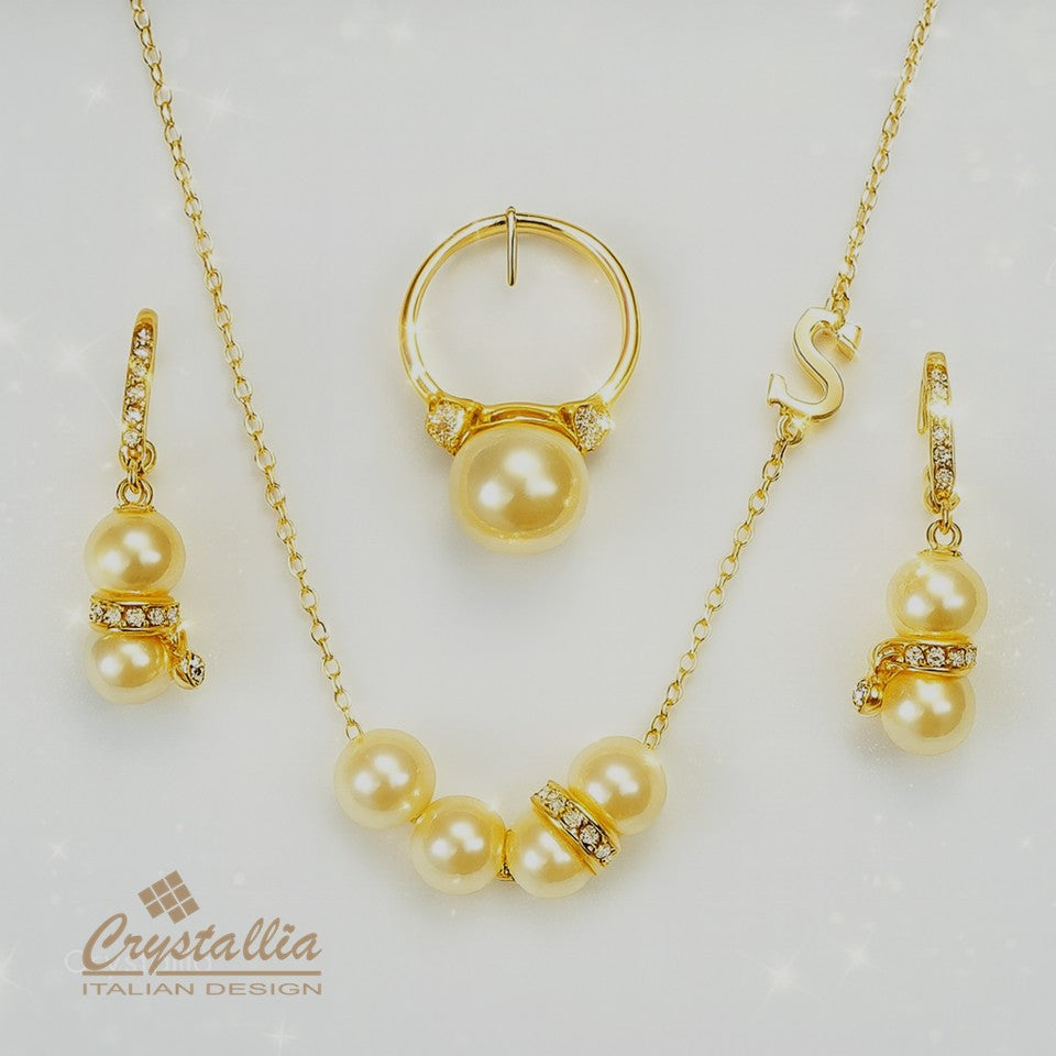 Gold jewelry set with pearls and Crystallia logo on a light background