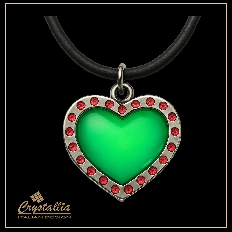 Heart-shaped pendant with green center and red accents on a black background, featuring the Crystallia brand.