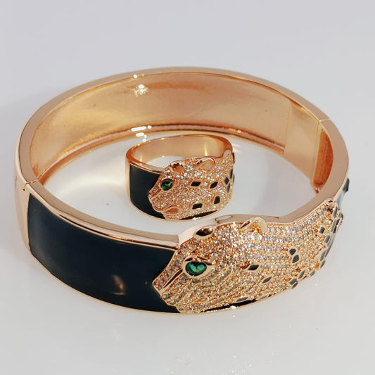 Gold and black bracelet with panther design on a light gray background
