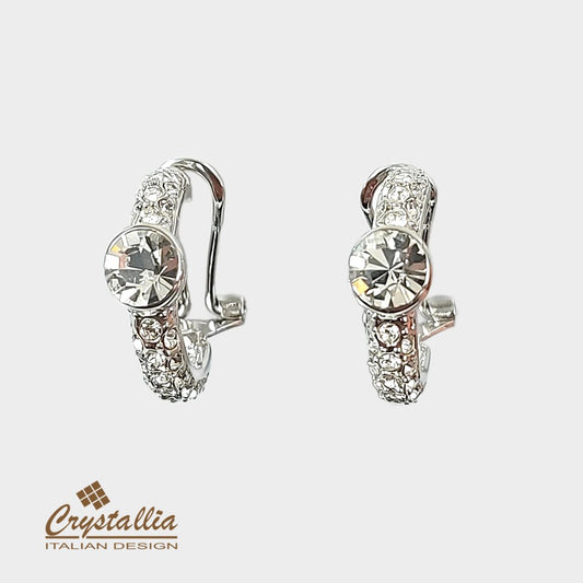Pair of silver hoop earrings with clear gemstones on a light gray background, featuring the Crystallia brand.