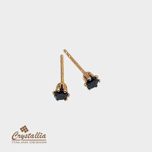 Gold earrings with black gemstones on a white background, featuring the Crystallia brand.