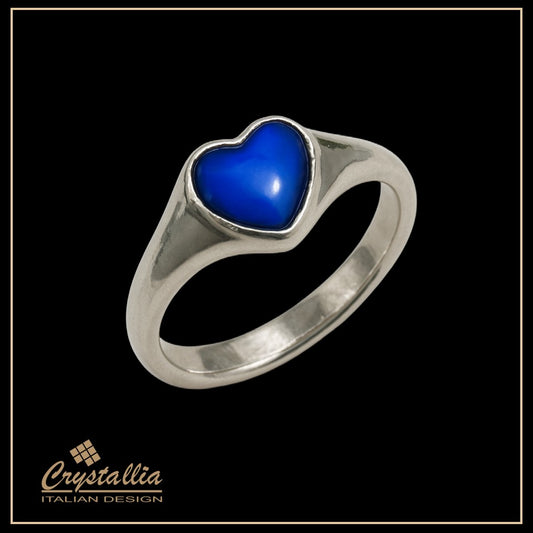 Silver ring with a blue heart-shaped stone on a black background, featuring the Crystallia brand.