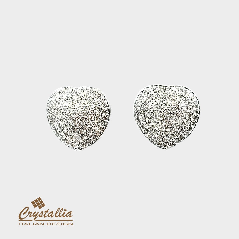 Heart-shaped silver earrings with glittery texture on a light gray background, featuring the Crystallia brand.
