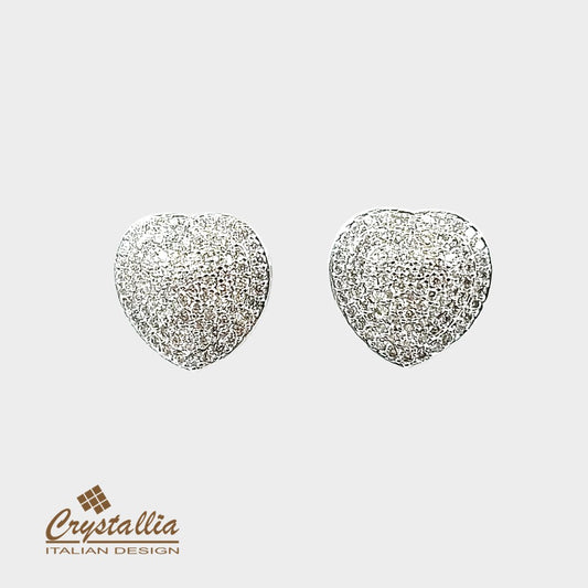 Heart-shaped silver earrings with glittery texture on a light gray background, featuring the Crystallia brand.