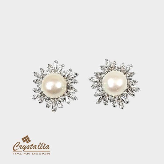 Pair of pearl earrings with diamond-like accents on a light gray background, featuring the Crystallia brand.