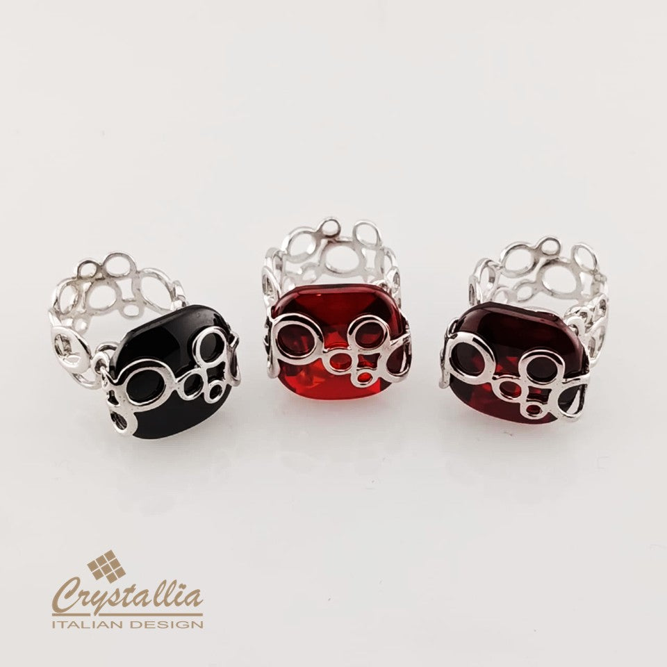 Three rings with black, red, and burgundy gemstones on a white background, featuring the Crystallia brand.