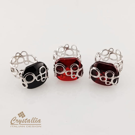 Three rings with black, red, and burgundy gemstones on a white background, featuring the Crystallia brand.