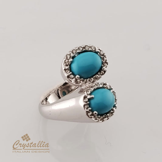 Silver ring with two turquoise stones on a light gray background, featuring the Crystallia brand.