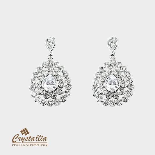 Pair of silver earrings with clear gemstones on a light gray background, featuring the Crystallia brand.