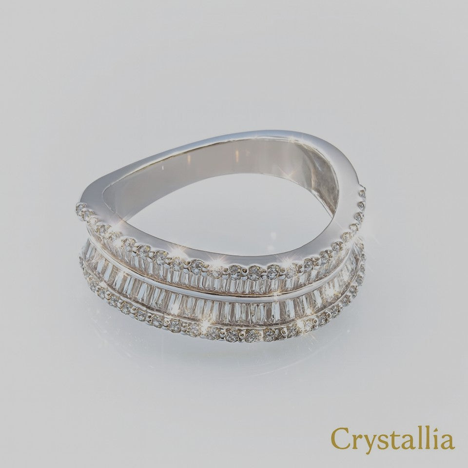 Stack of silver rings with diamond accents on a light gray background, branded 'Crystallia'.