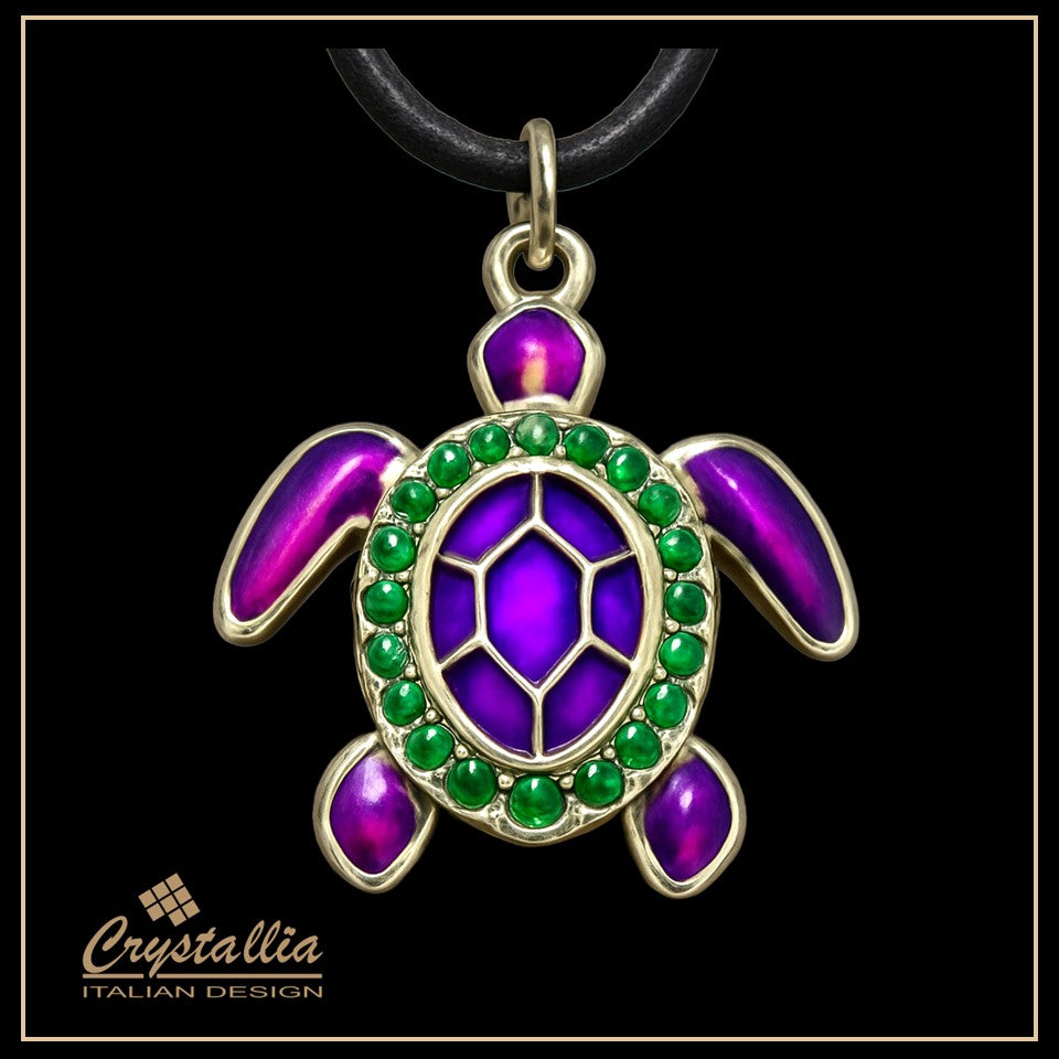 Tortoise-shaped pendant with purple and green gemstones on a black background, featuring the Crystallia brand.