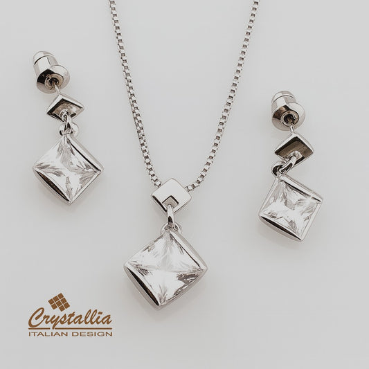 Silver necklace with square pendant and matching earrings on a light gray background, featuring the Crystallia brand.