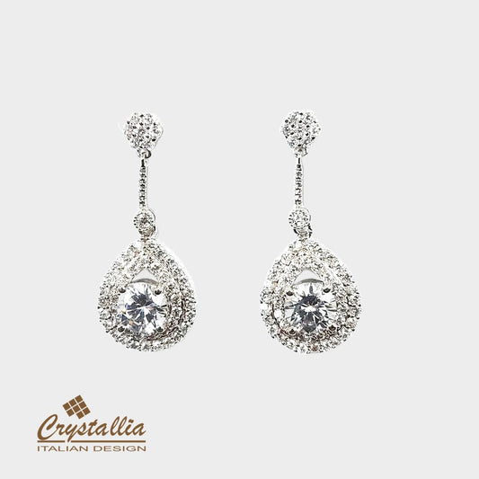 Pair of silver earrings with clear gemstones on a light gray background, featuring the Crystallia brand.